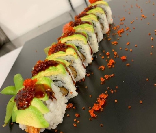 Line of sushi on a black plate, garnished with roe